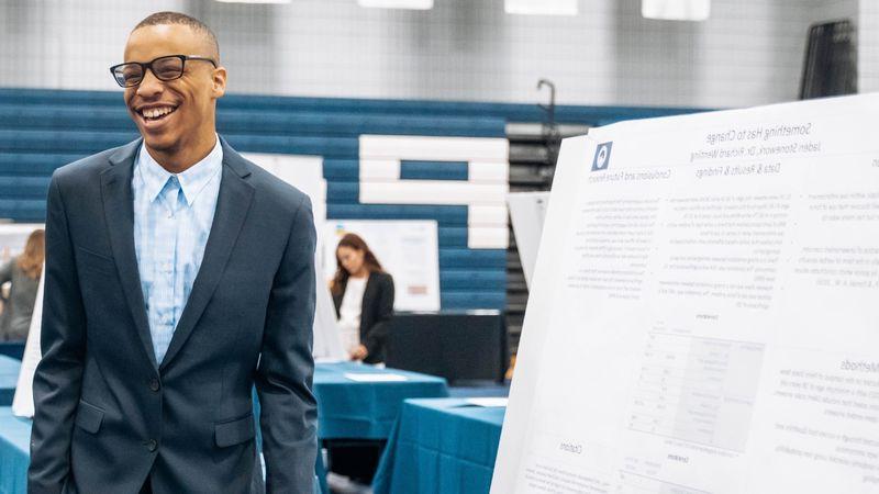 Student standing next to research poster